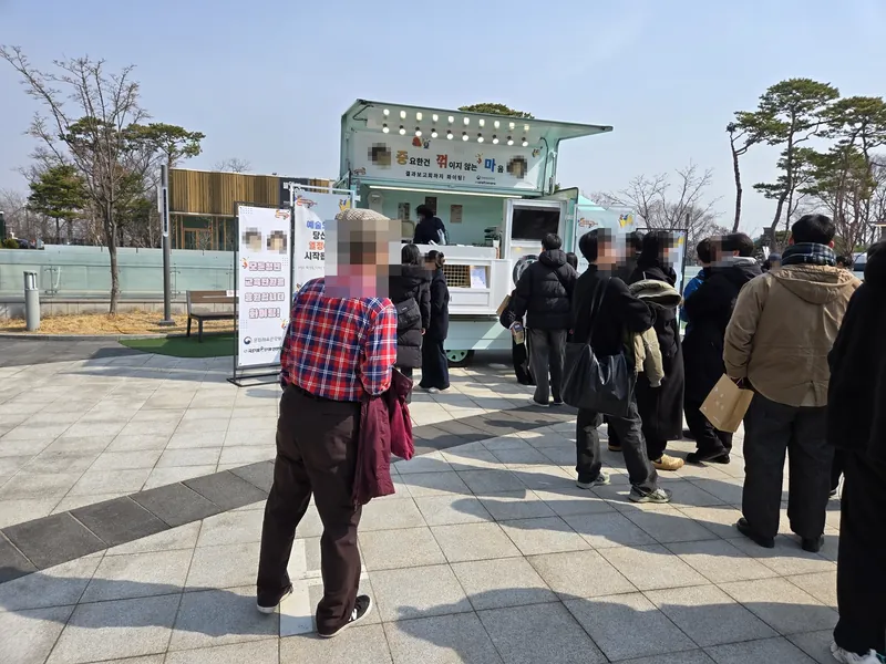 광장의 민트색 트럭 앞에 길게 줄 선 사람들