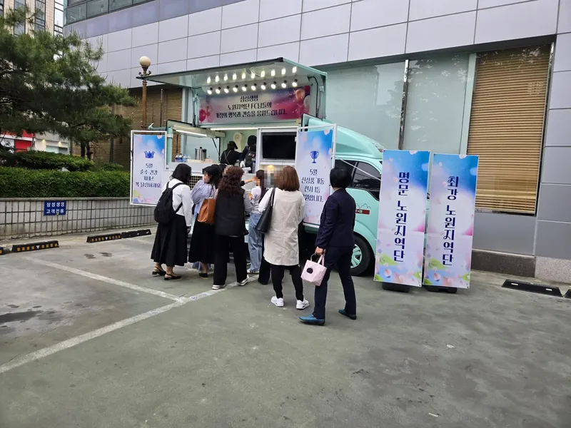 사무실 건물 앞에 선 민트색 커피투어트럭과 줄 선 직장인들