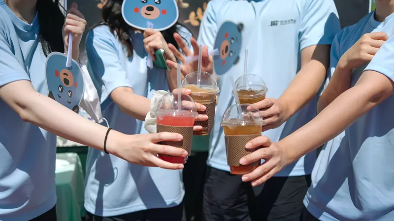 같은 티셔츠를 입은 대학생들이 음료를 모아 건배하는 모습